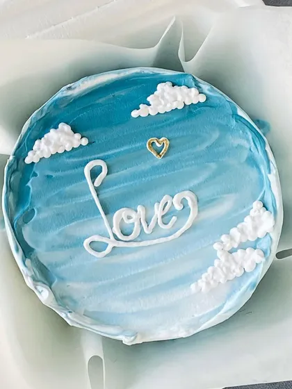 A dreamy blue bento cake with "Love" written across a sky of buttercream clouds. It's a sweet and simple gesture for an anniversary or just to show you care.