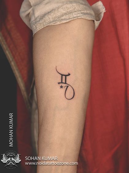 A minimalist tattoo combining the Gemini zodiac symbol with a client's initial. We can create custom symbols that merge different parts of your identity.