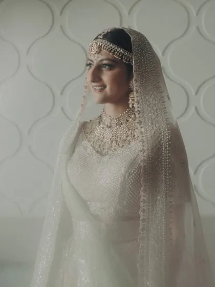 A bridal portrait that feels both grand and intimate. The bride, in her ethereal white lehenga, looks serene and beautiful, ready for her big day at the Taj Mahal Palace.