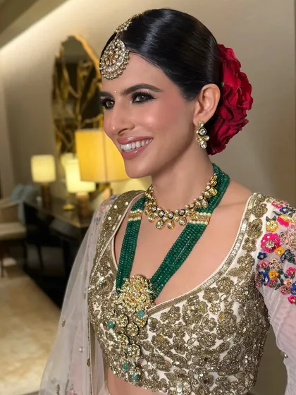 The bride's radiant smile is the perfect accessory for her elegant red rose bun and traditional attire.