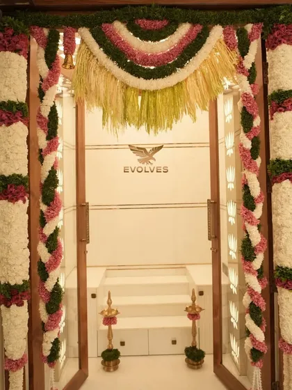 For traditional ceremonies like a house warming, the details matter. This pooja room entrance is decorated with intricate flower garlands, combining classic floral work with a clean, modern aesthetic to create a welcoming and auspicious entryway.