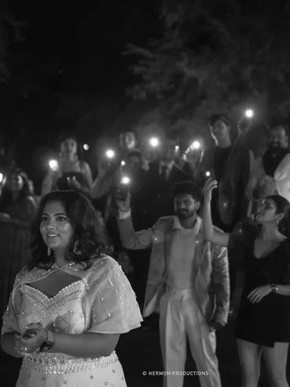 Guests hold up their phone flashlights, creating a sea of stars for the bride during a special moment at the reception.