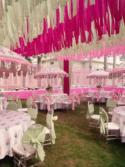 An elegant Mehendi setup combining hot pink and mint green. The space is filled with custom-printed umbrellas and tablecloths for a cohesive and charming look.