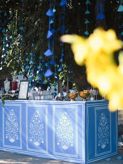 The bar for the blue and yellow Haldi, featuring a custom front with blue pottery motifs. The tree behind was decorated with hanging blue paper tassels, tying the whole look together.