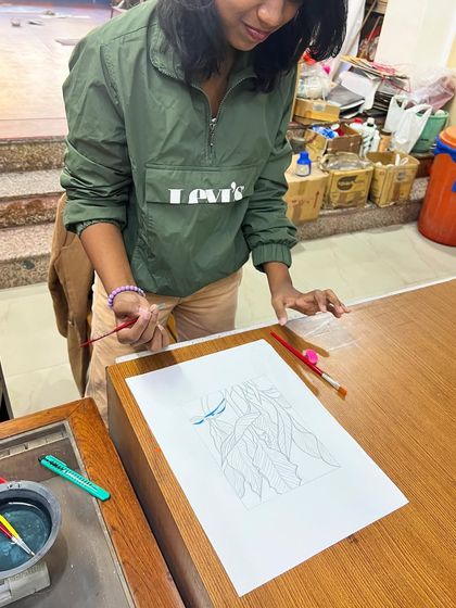 A student carefully painting her design, the first step before it gets transferred to the silk screen for printing.
