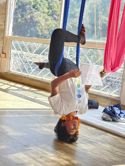 Even when you're upside down, the learning never stops. This was me during my Aerial Yoga teacher training in Rishikesh, studying human anatomy while hanging in an inversion. It shows my commitment to understanding the body so I can teach you to move safely and effectively.