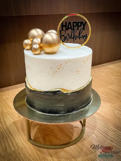 A sophisticated black and white buttercream cake with a fault line design and gold accents. This is a great choice for a milestone birthday.