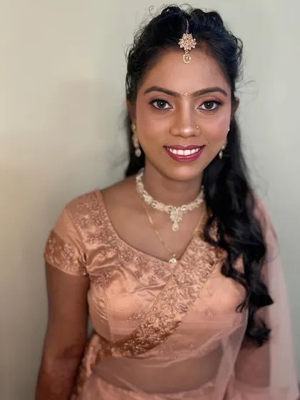 The final engagement look for this North Indian bride. She looks radiant and happy in a peach-colored saree with soft, romantic makeup and hairstyle.