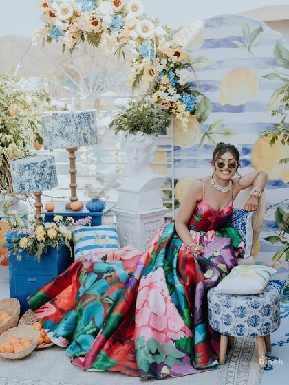A stunning portrait of the bride at her colorful, Italian-themed pre-wedding carnival. Her vibrant floral gown and the chic decor create a high-fashion look.