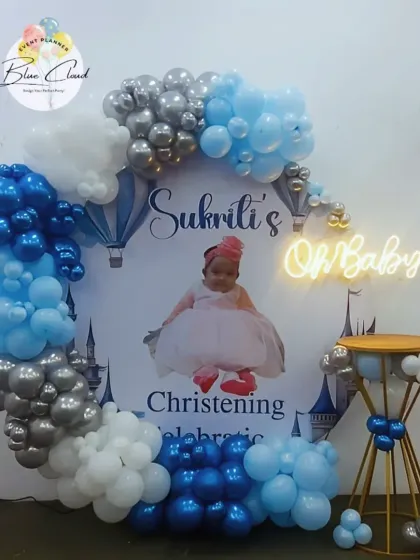 A Christening and 'Oh Baby' celebration with a custom photo backdrop and a blue, white, and silver balloon garland.