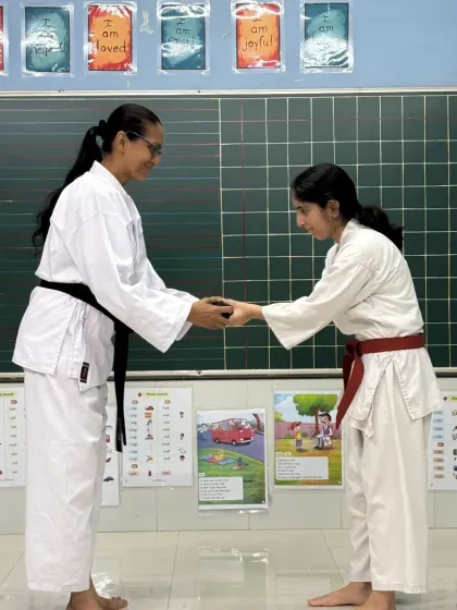 A moment of profound respect. A student bows as she receives her new belt from her Sensei, a traditional gesture symbolizing gratitude and the formal acceptance of a new level of responsibility in her training.