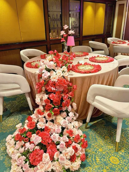 A table with a cascading floral runner made of red and pink roses, designed for the same event.