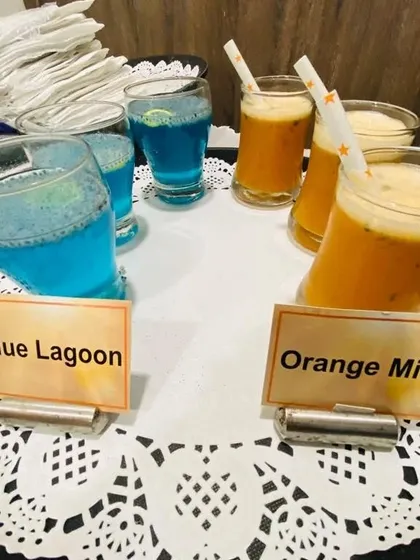 We offer a colorful variety of mocktails to welcome your guests. This tray shows our popular Blue Lagoon and Orange Mint drinks, perfect for adding a festive touch to any celebration.