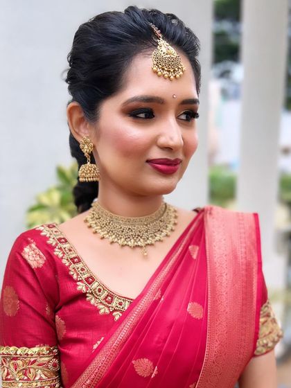 A classic red and gold combination for an engagement. This look features a soft smokey eye and a bold red lip, a timeless choice for any South Indian bride.