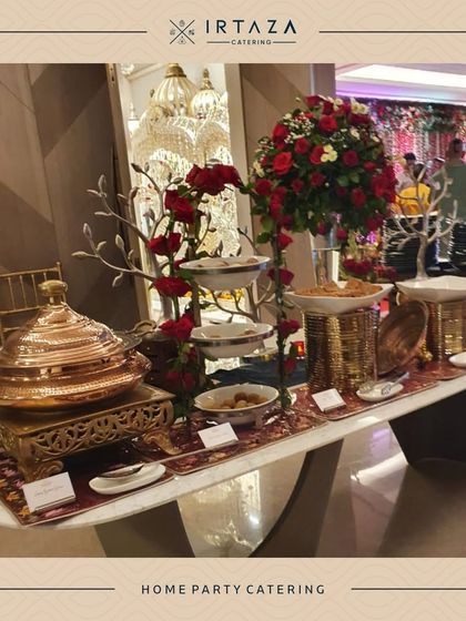 An opulent home party setup featuring a stunning floral arrangement of red roses and tiered serving dishes, creating a truly luxurious focal point.