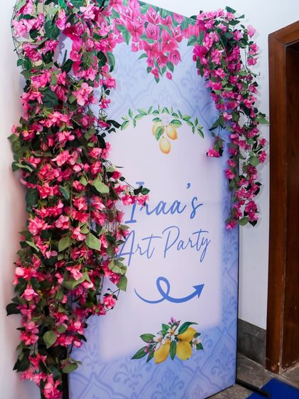 A lovely entrance sign for "Iraa's Art Party," decorated with pink bougainvillea flowers to match the Greek theme.