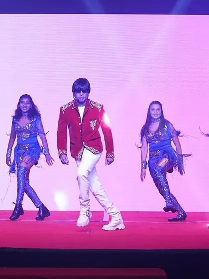 A performance in a red jacket and white pants, with my dancers in sparkling blue costumes. We use costume changes to keep the show visually exciting.