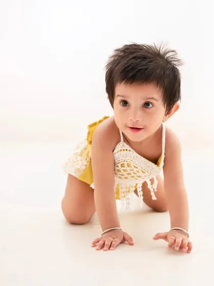 A crawling shot that captures a baby's natural curiosity and movement. The clean, bright background keeps the focus on the child.