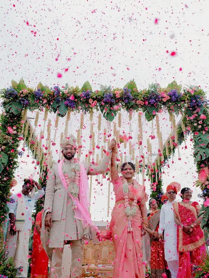 A moment of pure celebration as the happy couple is showered in flower petals under a stunning floral mandap. This is the kind of joyful, vibrant memory I love to capture, freezing the peak of happiness in time.