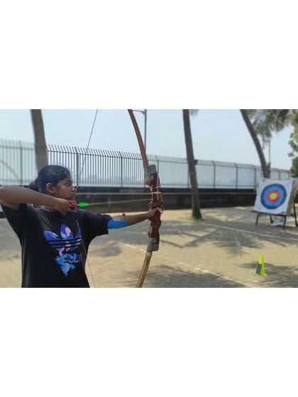 A student in mid-shot, showing the dynamic motion of releasing an arrow.