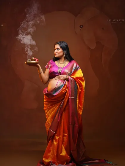 A spiritual and serene portrait, with the mother-to-be holding a diya. The bare baby bump is a beautiful focal point, celebrating the life within.