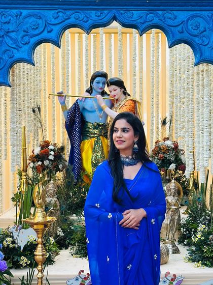 A moment of calm before the storm of activities. Standing before a stunning Radha-Krishna setup at a wedding event.