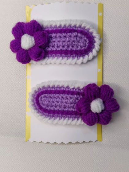 A pair of Korean-style hair clips in shades of purple and white with a flower accent.
