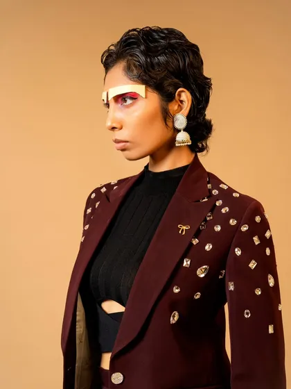 A creative portrait for a designer lookbook, focusing on a jewel-encrusted blazer. The unconventional makeup and styling give the shot an avant-garde edge.