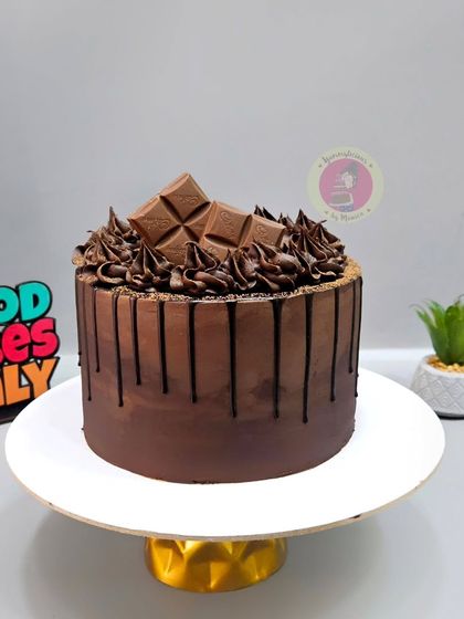 A classic chocolate drip cake, generously topped with chocolate chunks and swirls of ganache.