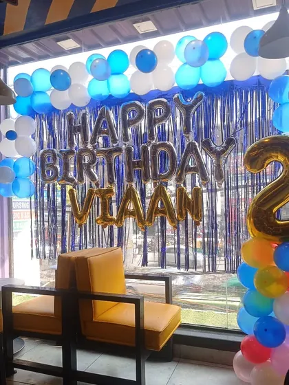 A simple yet effective birthday decoration on a large window. This setup with a balloon garland and foil letters is great for cafes or restaurants.