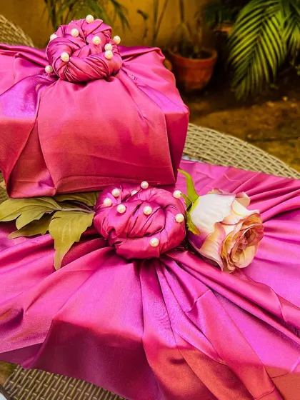 My luxury trousseau packing service transforms your gifts into works of art. Here, presents are wrapped in regal magenta satin fabric, finished with intricate pearl detailing and a delicate rose accent, ensuring the presentation is as memorable as the gift inside.