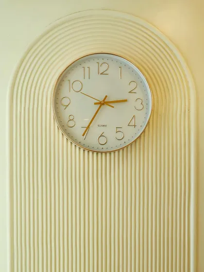 A close-up of the wall clock set within a fluted arch, a small detail that reinforces the room's cohesive design theme.