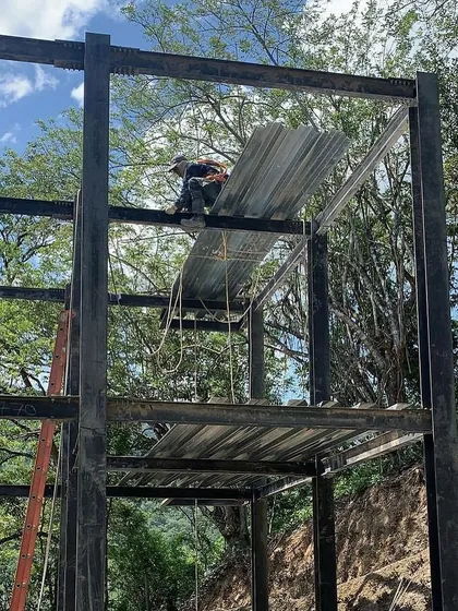 A worker installing the metal decking for the second floor of a modular home. This highlights the systematic and safe construction methods we employ on all our project sites.
