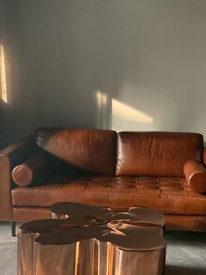 A shaft of sunlight falls on a classic tan leather sofa, highlighting its rich texture and color.