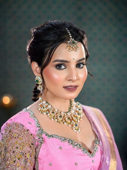A close-up portrait focusing on the makeup and jewelry details of the half-saree look.