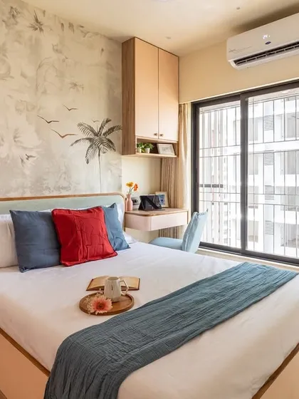 This wide shot of the botanical-themed bedroom highlights the abundant natural light and the seamless integration of the wardrobe and study area.