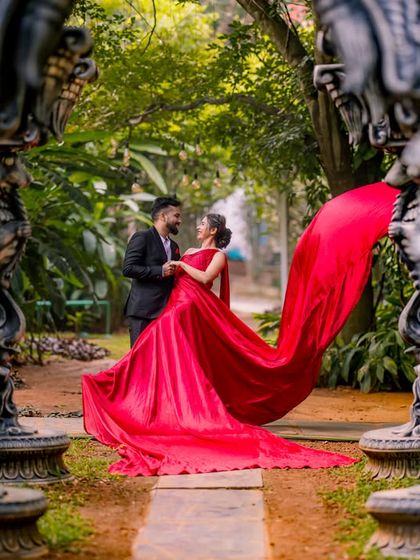 A dramatic shot of a flowing red dress framed by ornate stone pillars in our garden.