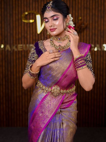 A stunning purple and gold Kanchipuram saree. The draping style is grand and traditional, perfect for a classic bridal photoshoot.