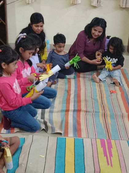 Children and parents work together to create "Hairy Hettie" puppets from paper rolls and yarn.