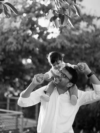 A joyful black and white photo celebrating fatherhood. The happiness on both the father's and son's faces is palpable in this classic outdoor portrait.