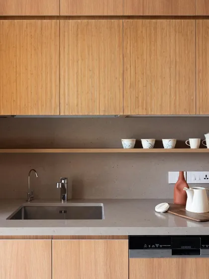 The fine, vertical lines of these solid wood fluted cabinets add a sophisticated texture that contrasts beautifully with the smooth, solid surface of the countertop and sink area.