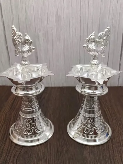 A pair of German silver Nakashi deepams, featuring a classic design and a peacock top. A timeless addition to any pooja room.