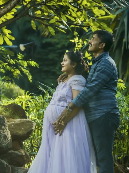 A candid moment of a couple looking towards their future together, framed by lush greenery. I use natural light to create soft, romantic outdoor maternity portraits.