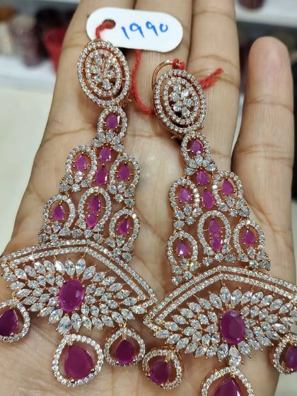 A pair of heavy American Diamond earrings with ruby stones and a rose-gold polish. The design is very unique and modern.