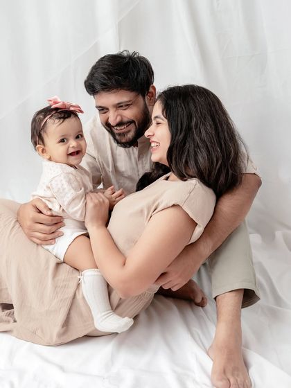 A sweet family moment on a simple white backdrop. The neutral outfits ensure that the focus remains on their happy interactions.