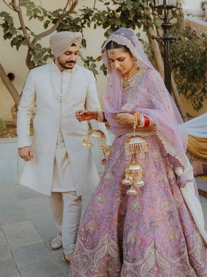A candid moment of a Sikh couple walking together after their Anand Karaj, the bride adjusting her beautiful kalire.