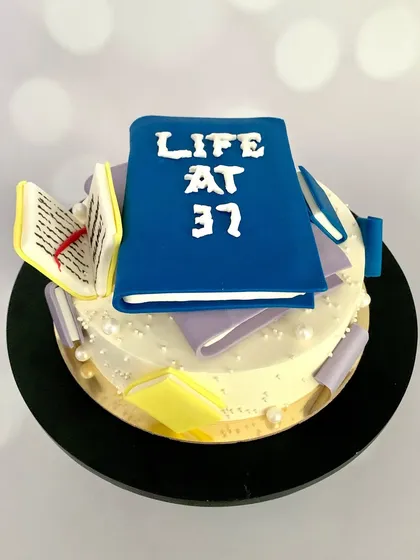 A side view of the book-themed cake, showing the tiny, edible, handcrafted books scattered around.