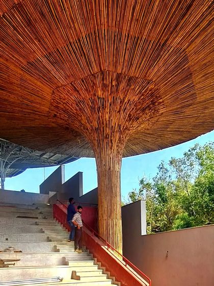 The scale of the bamboo parasol is evident in this construction shot, as workers stand on the steps of the amphitheater below.