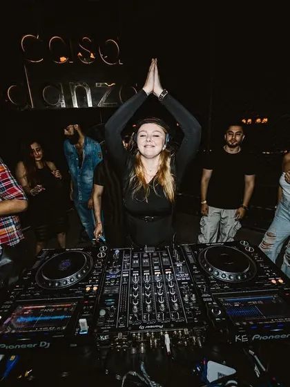 A moment of gratitude and connection with the crowd, making a 'namaste' gesture from the booth.