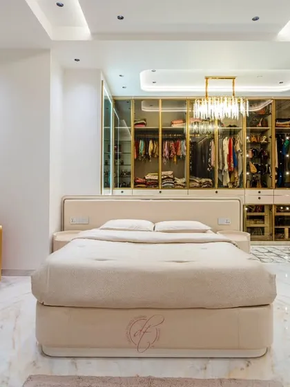 This master bedroom is a sanctuary of tranquility and style. We designed it around an open, walk-in closet with glass and gold-trimmed doors, creating a stunning focal point. The space is a testament to our belief that a bedroom should be both a personal retreat and a masterpiece of design.